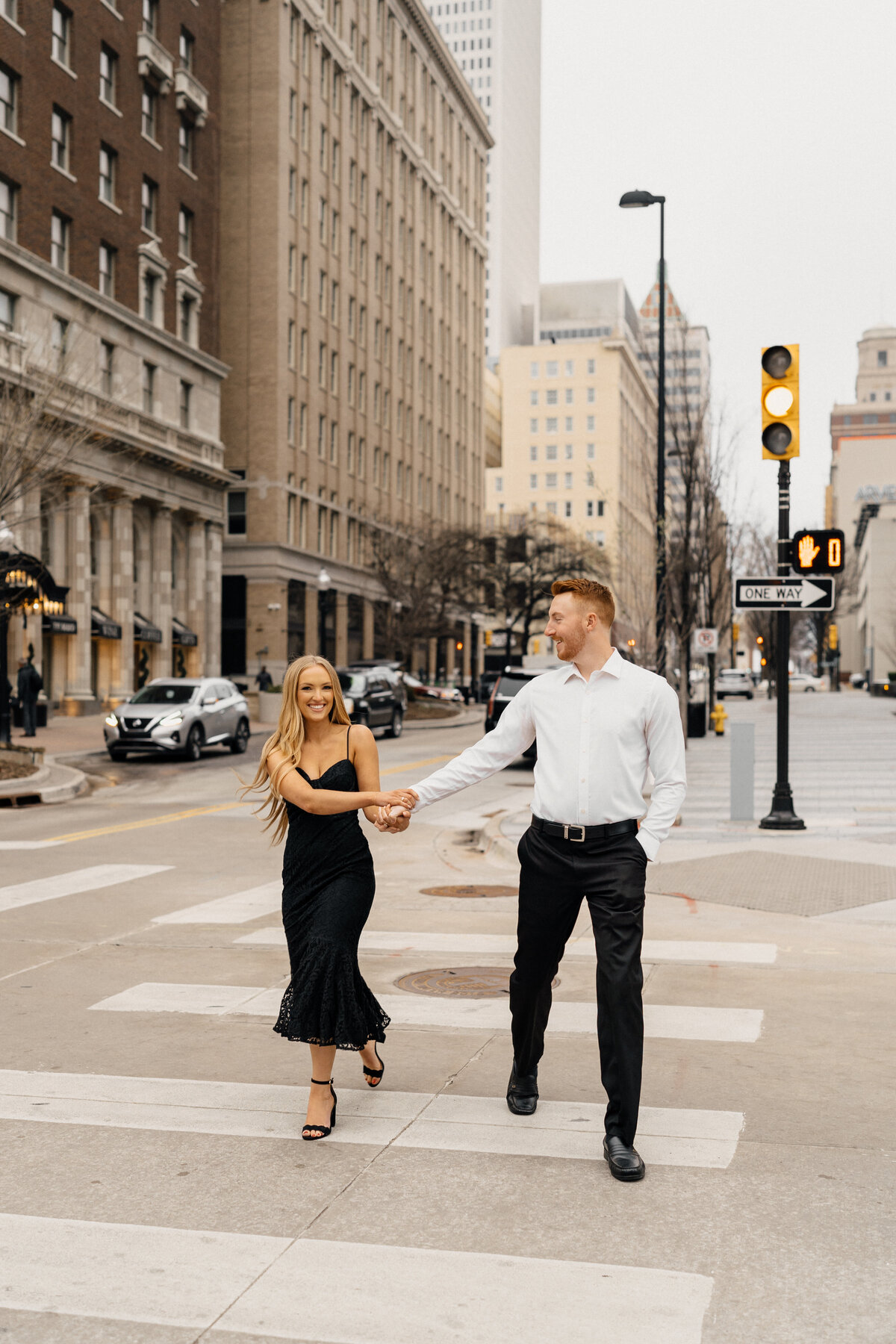 Romantic engagement photography with a couple dancing under city lights in downtown Tulsa, Oklahoma.