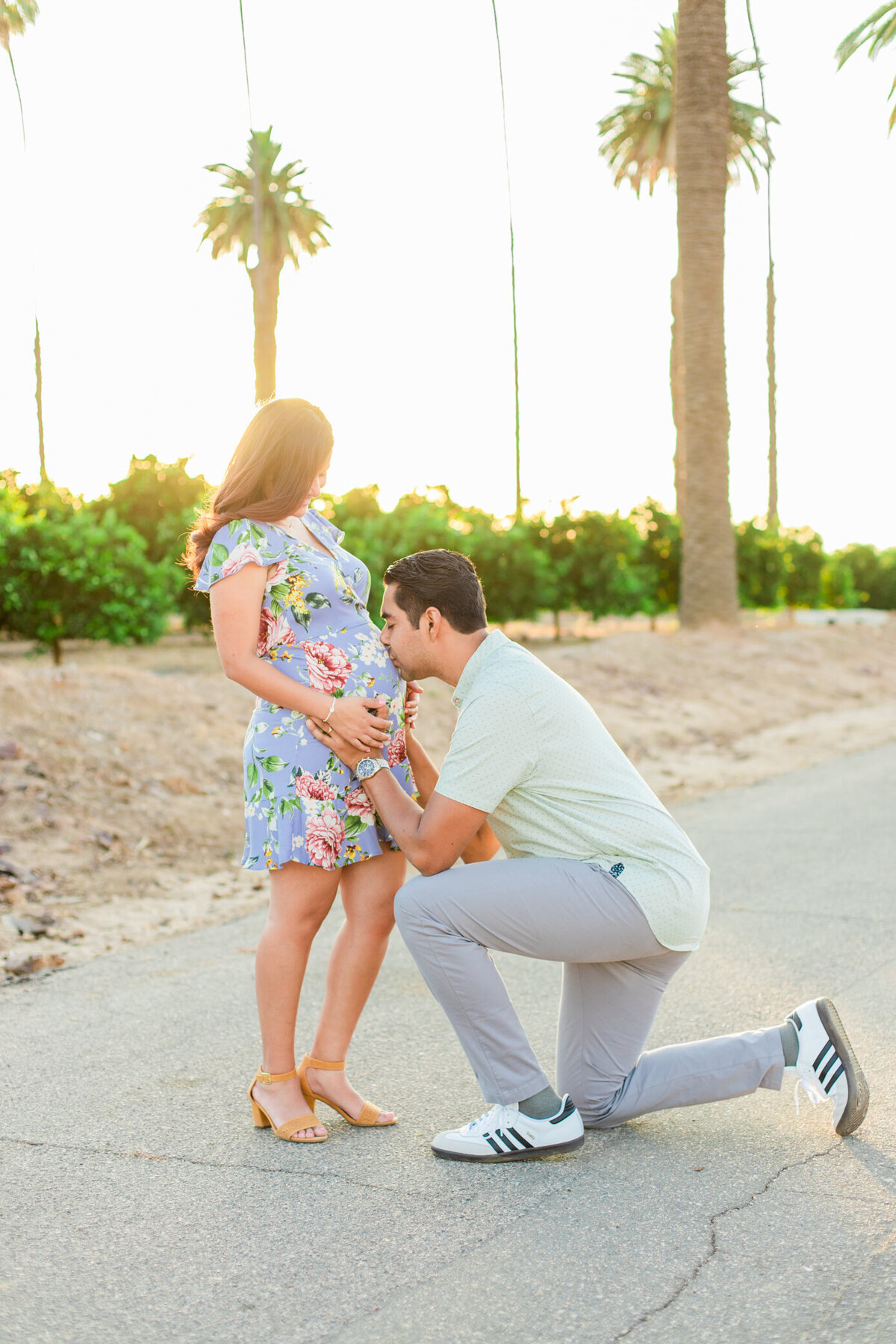 dad kisses moms belly on one knee