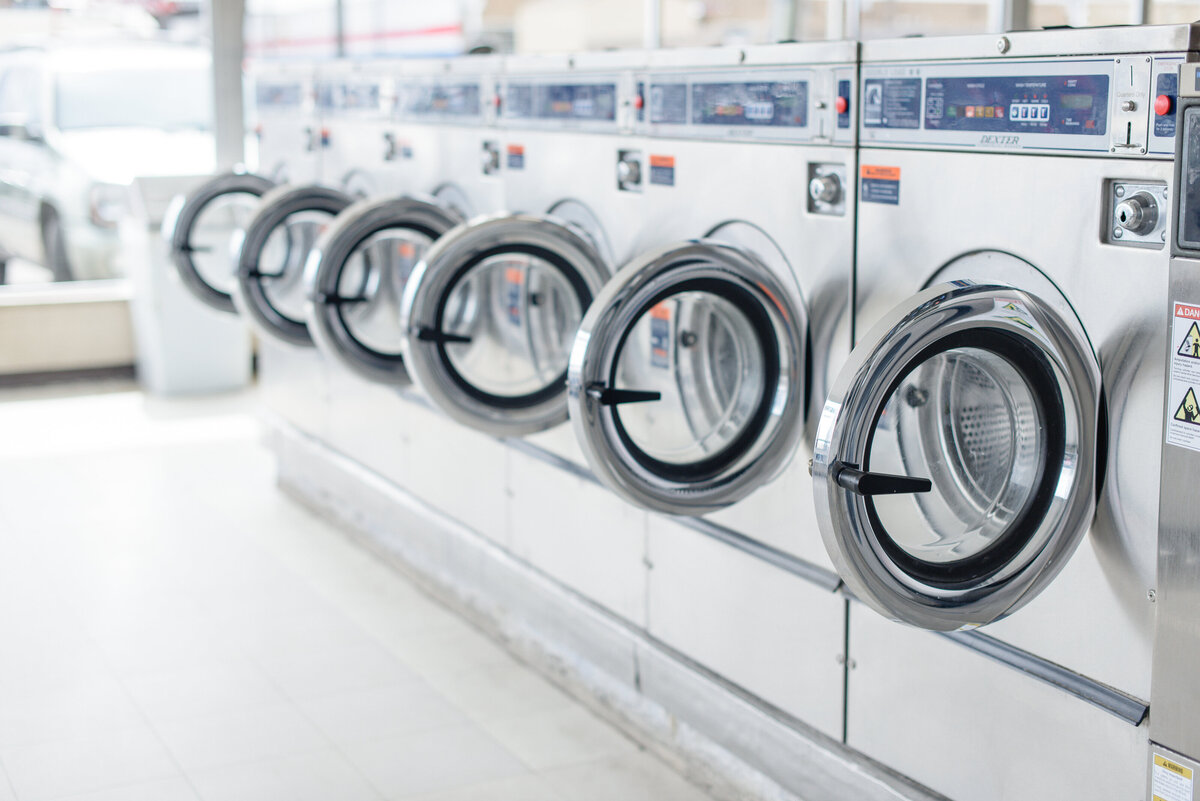 A commercial photographer near me takes an image of a line of washing machines in a white laundromat