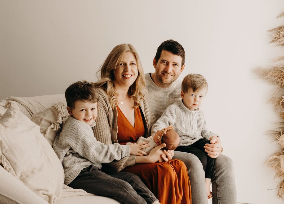 Happy family of five (parents, two sons, and a newborn) in a cozy studio portrait in Mullingar