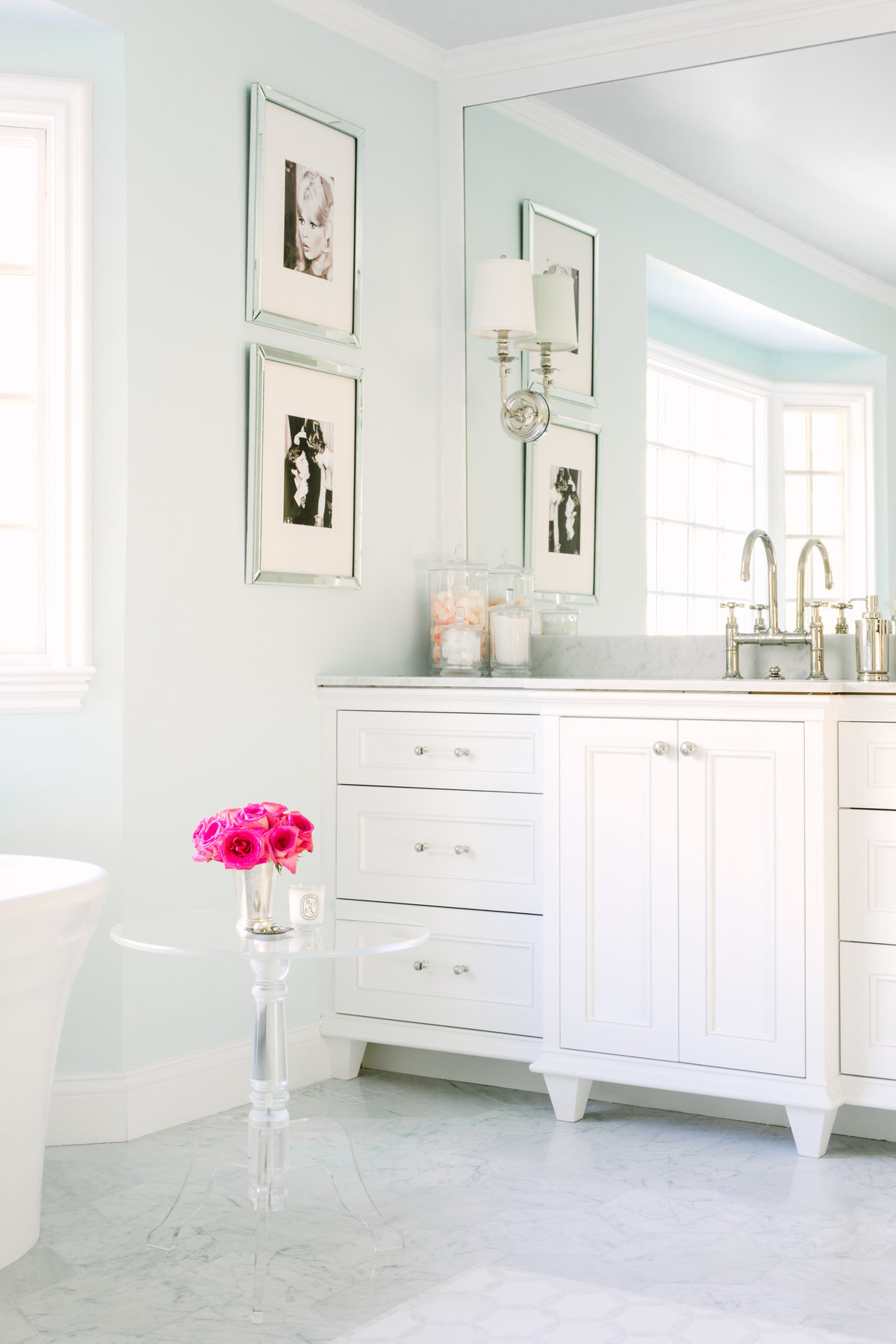 Master bathroom with light blue walls, Carrara marble hexagon floors, white vanities with built in mirror and sconces on top of mirror