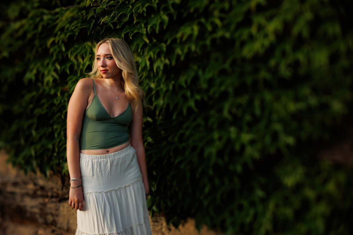 Maria stands in front a green leafy wall.