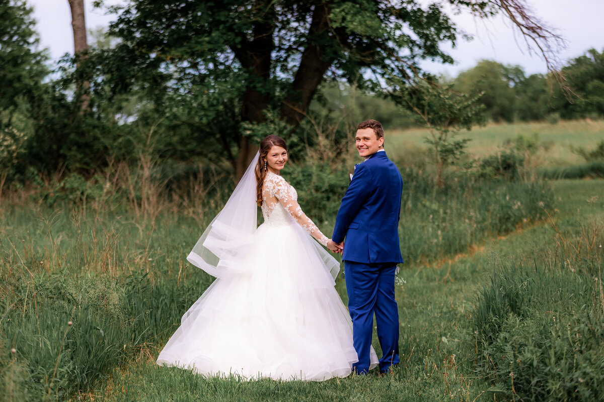 Bride and Groom turn back to smile at the camera during a romantic walk.
