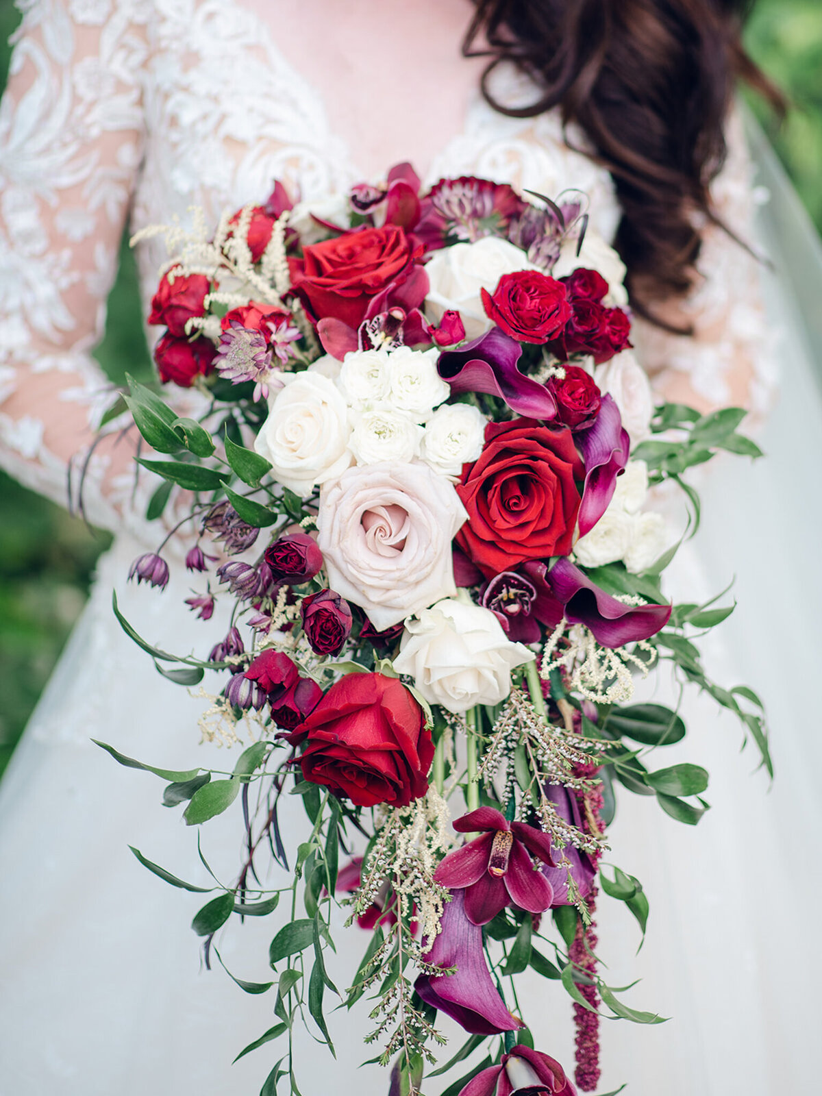 Stunning cascading bouquet of red and white roses by Flower Aura By Natasha, classic Calgary, Alberta wedding florist, featured on the Brontë Bride Vendor Guide.