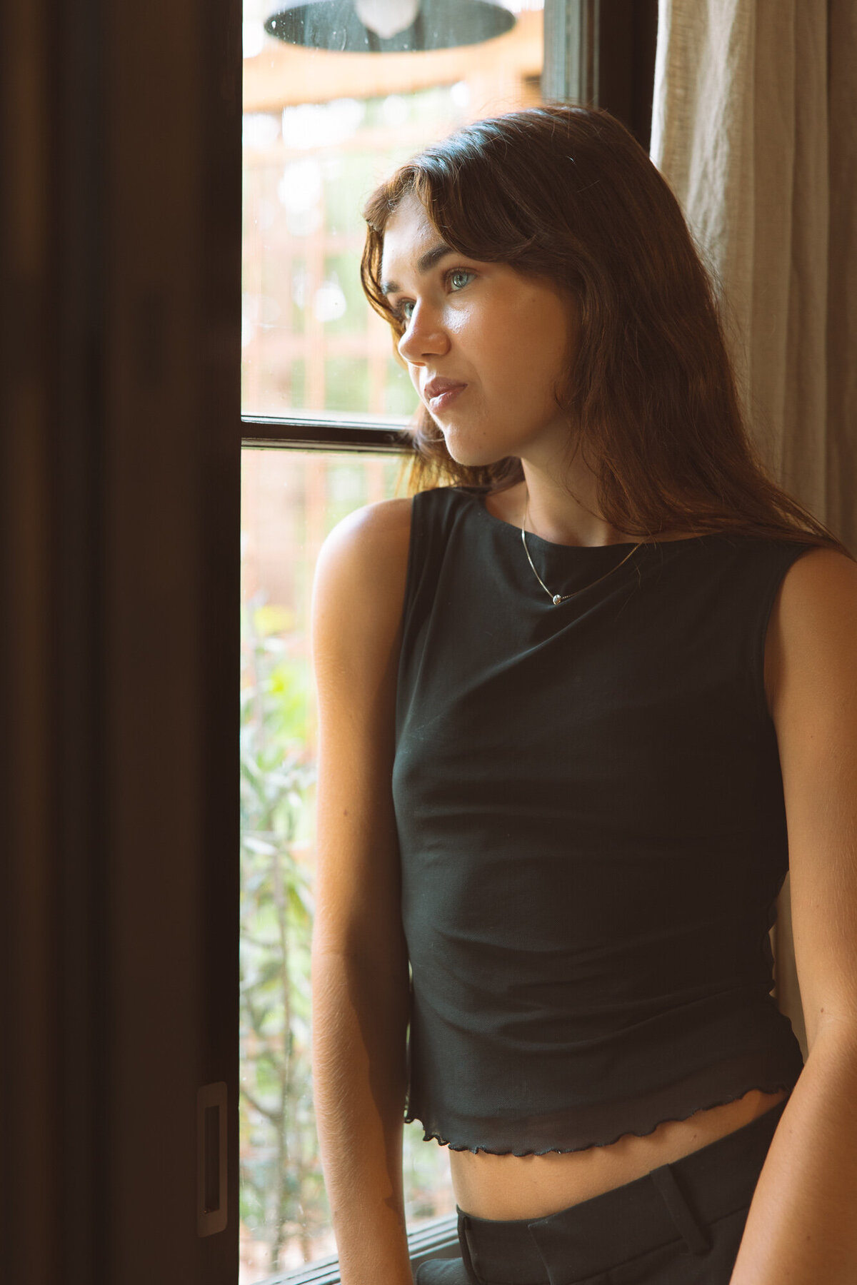 Soft, observational portrait of a woman by the window, shot by a Sunshine Coast branding photographer for a lifestyle-focused brand.