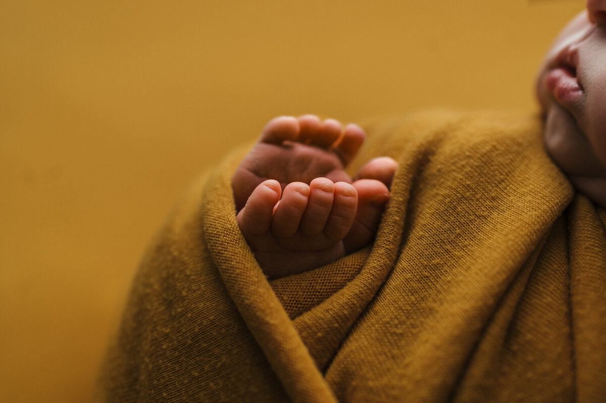 Baby wrapped in yellow with toes sticking out