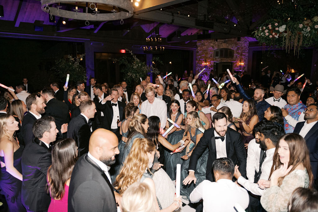 Guests fill the dance floor waving LED glow sticks at an energetic wedding reception at Old Edwards Inn in Highlands, NC.
