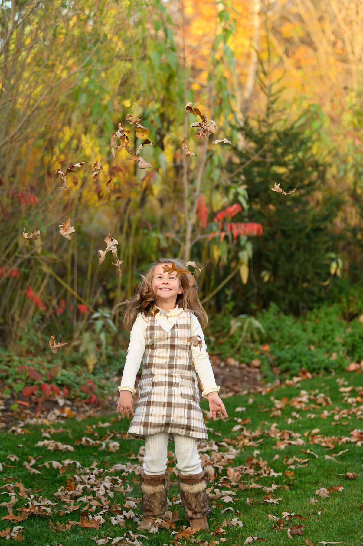 Little girl throwing leaves in their air for her fall family photos