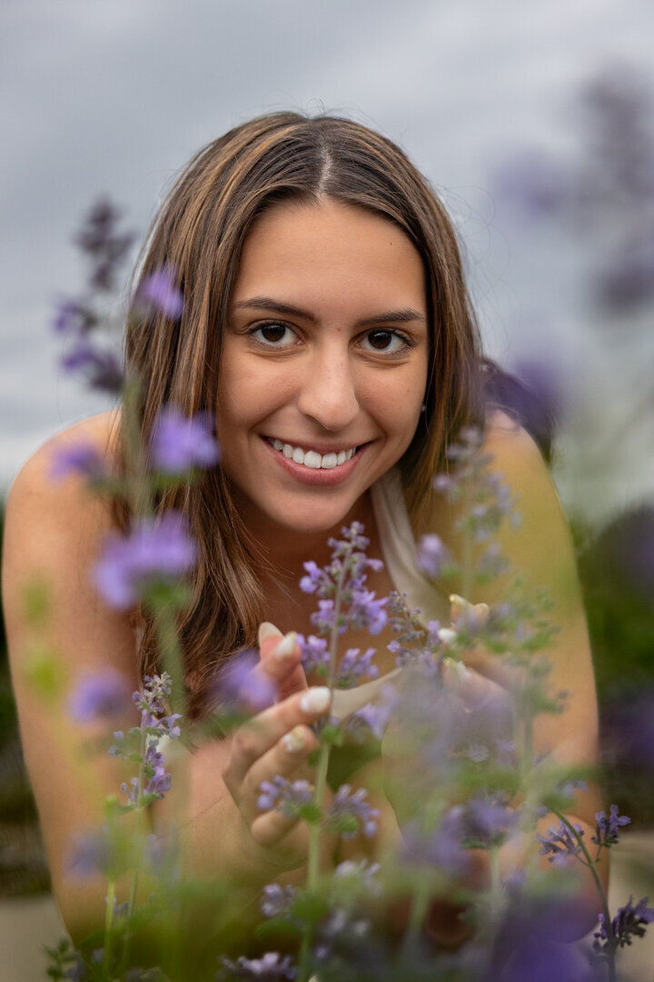 A senior girl smelling purple flowers in Lawrence KS