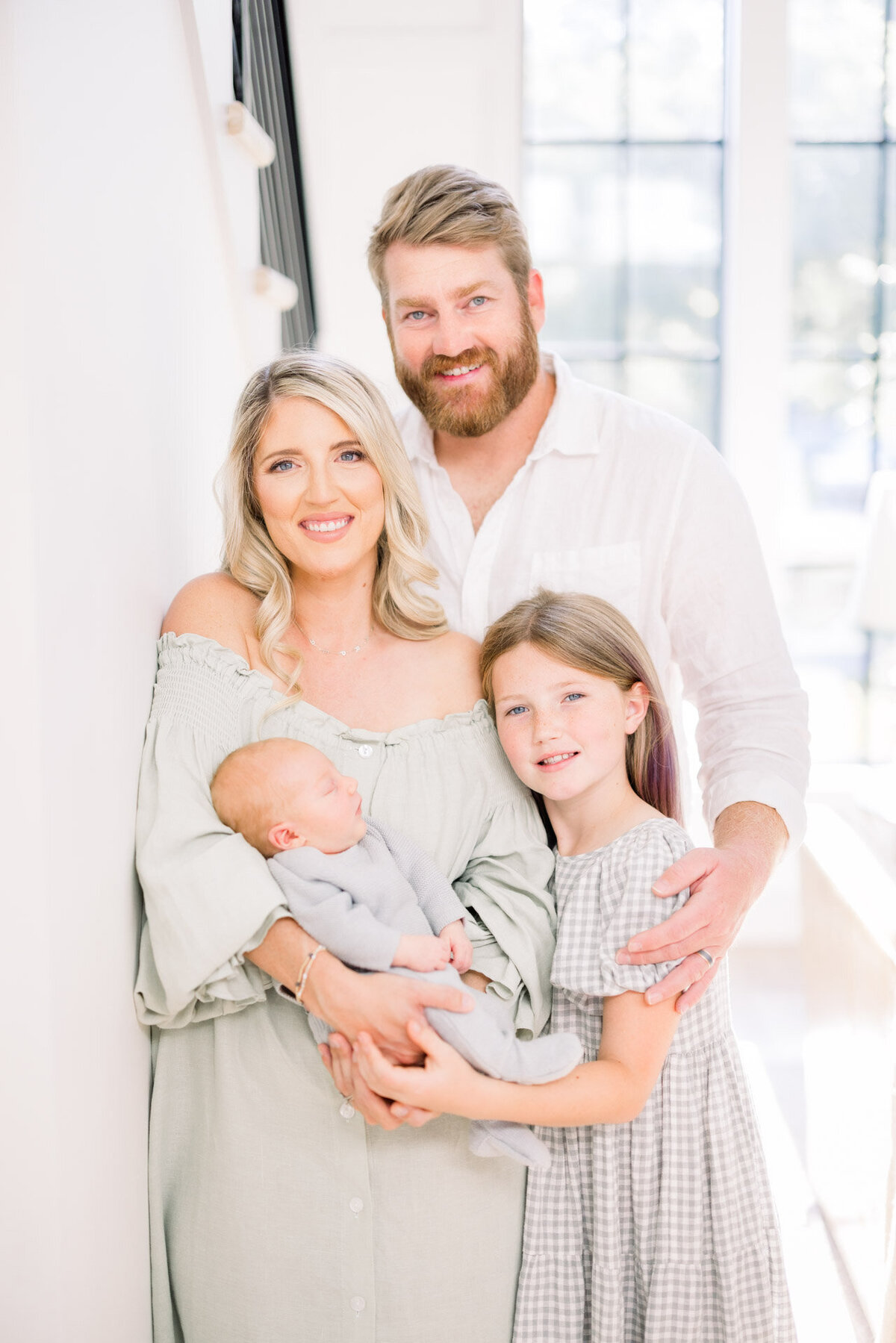 family holding baby and smiling at camera for Tampa newborn photographer Tina Marie Studio.