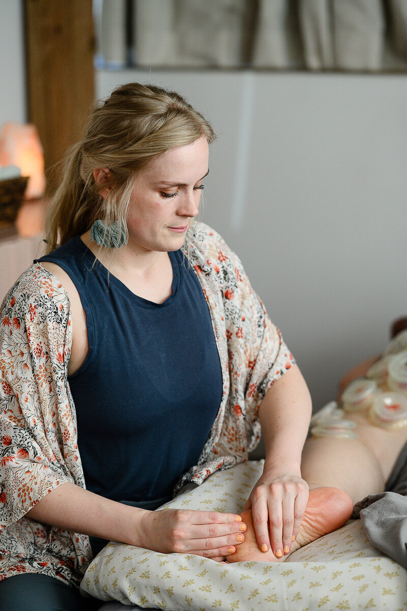 A branding photographer in Denver takes a picture of a woman doing a foot massage during a brand photoshoot and branding photography session.