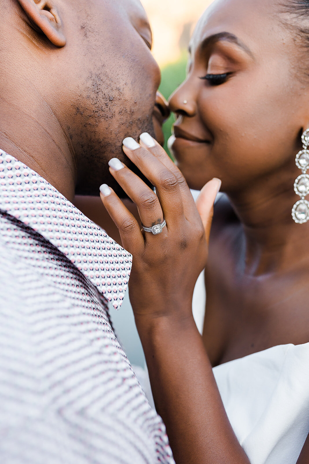 Man and woman kissing with the focus on the engagement ring