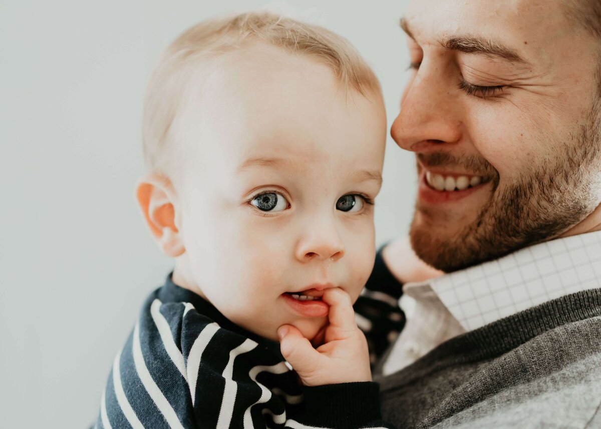 A man is gently holding a baby in this heartwarming photo, captured by a Pittsburgh family photographer.