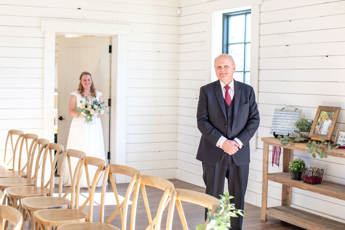 bride approaches father from behind in doorway at Morgan Creek Barn in Dripping Springs Texas