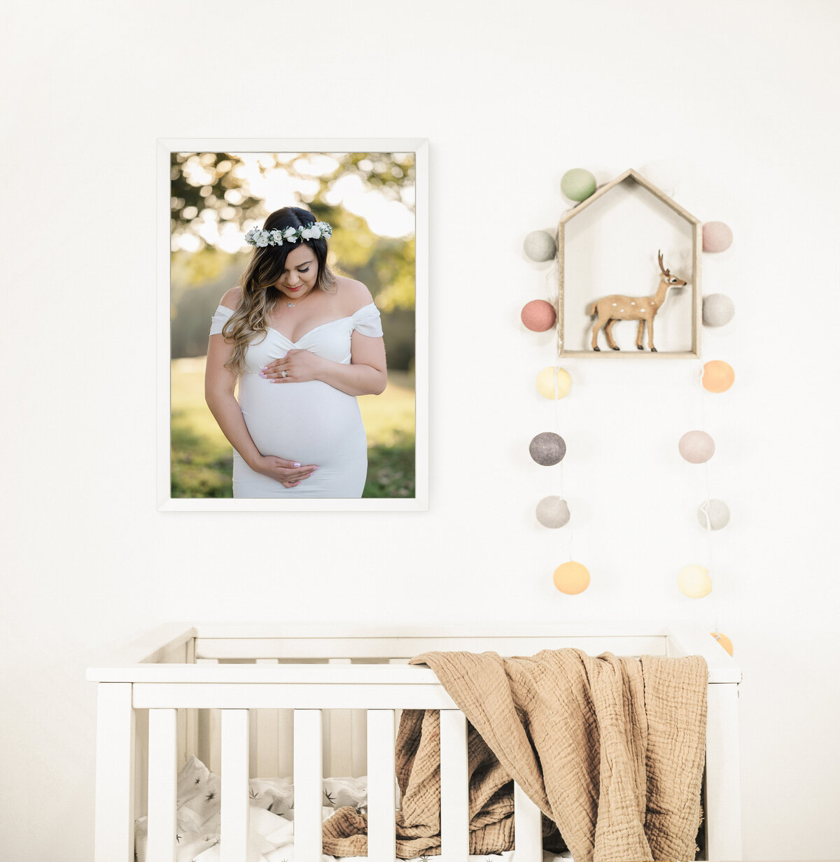 Expecting mother wearing a white dress and flower crown gazes at her belly. Maternity photos by Amanda Touchstone