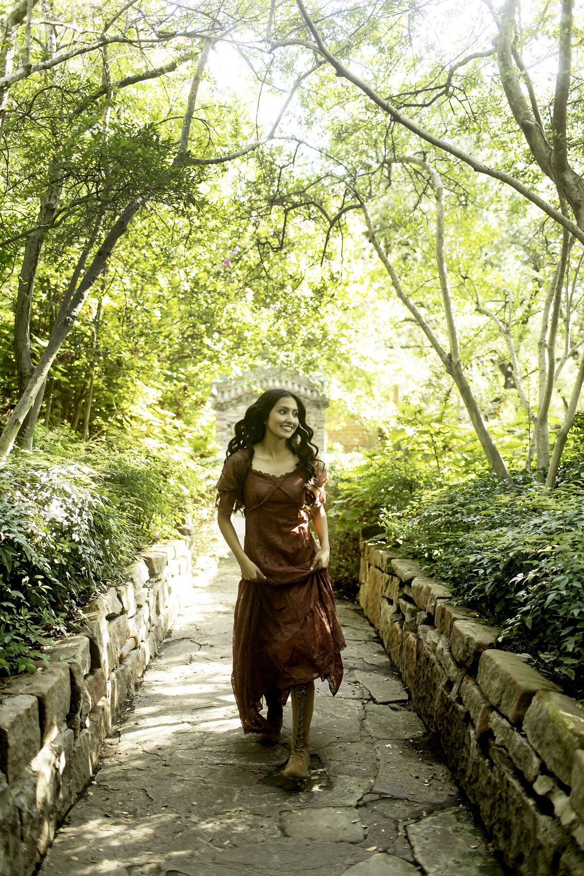 Captured in a candid moment, a senior smiles as she strolls through the peaceful gardens of Chandor Gardens, Weatherford, TX, embodying both grace and excitement