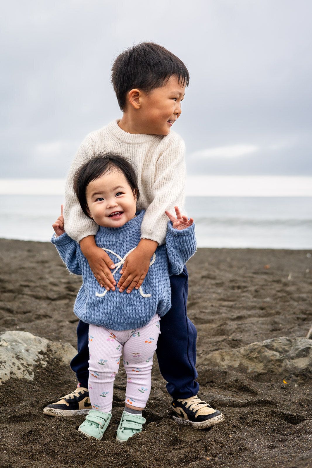 Siblings hugging and smiling on the beach during Bay Area school photography lifestyle session – Ellobelle Photography