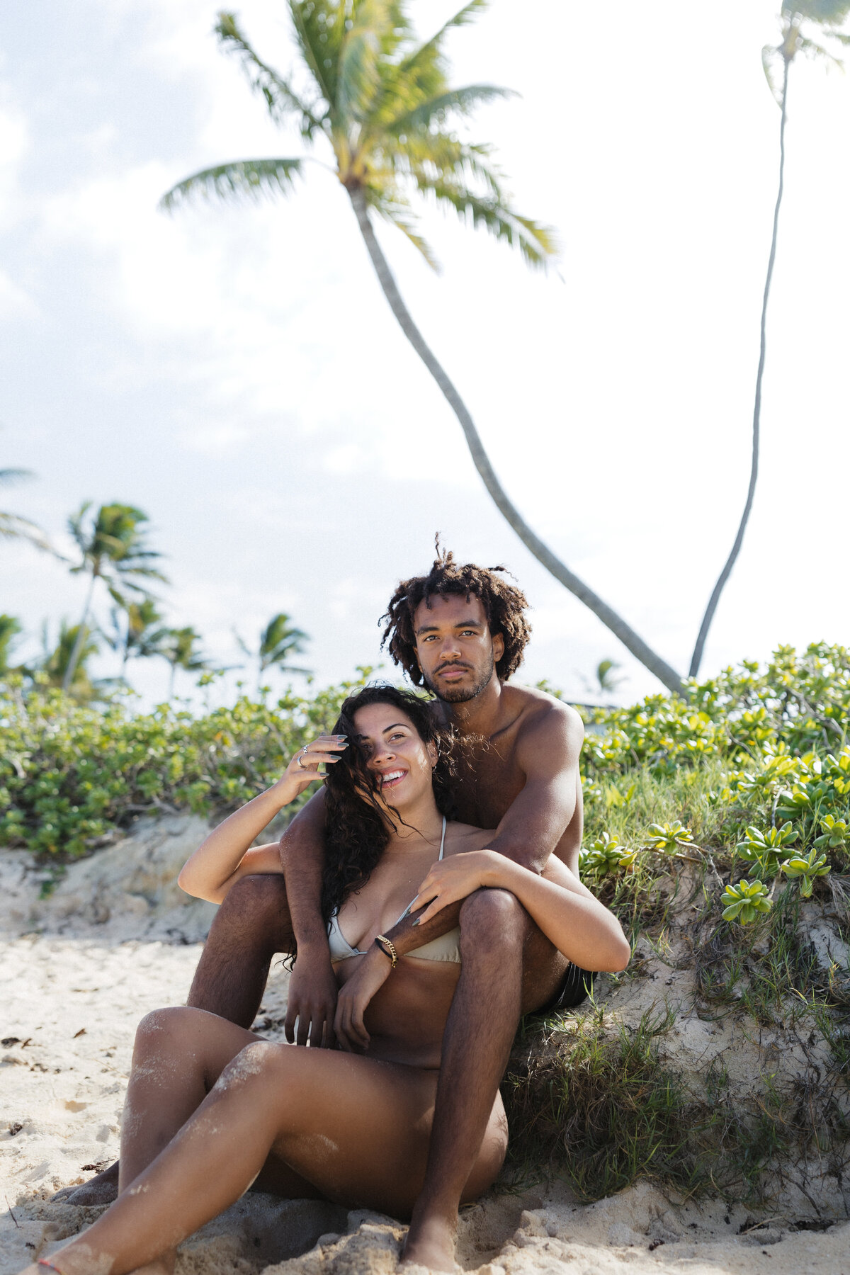 A couple embracing on a tropical beach in Hawaii, captured in a cinematic documentary wedding photography style.
