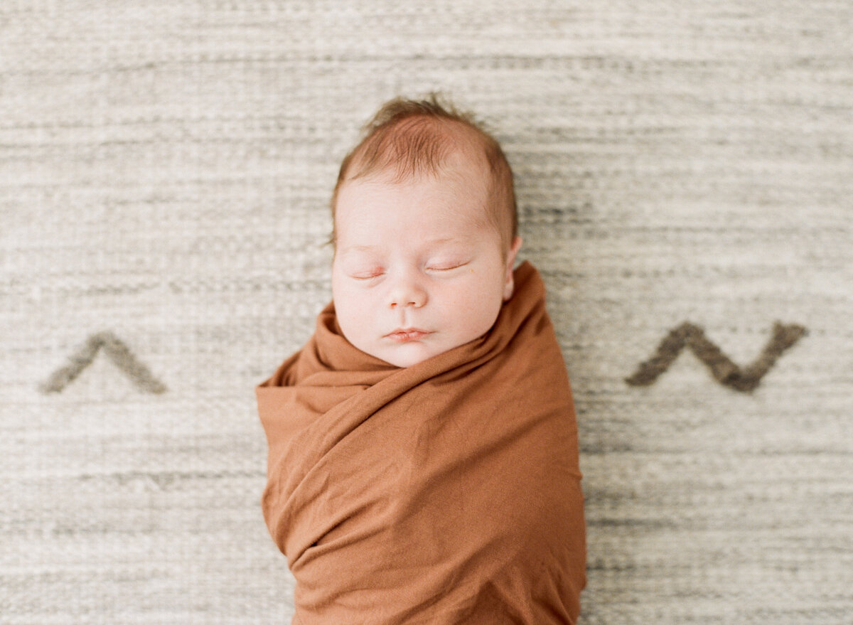 Baby lays sleeping for a portrait during his Raleigh NC newborn session while swaddled. Photographed by Newborn Photographers Raleigh A.J. Dunlap Photography.