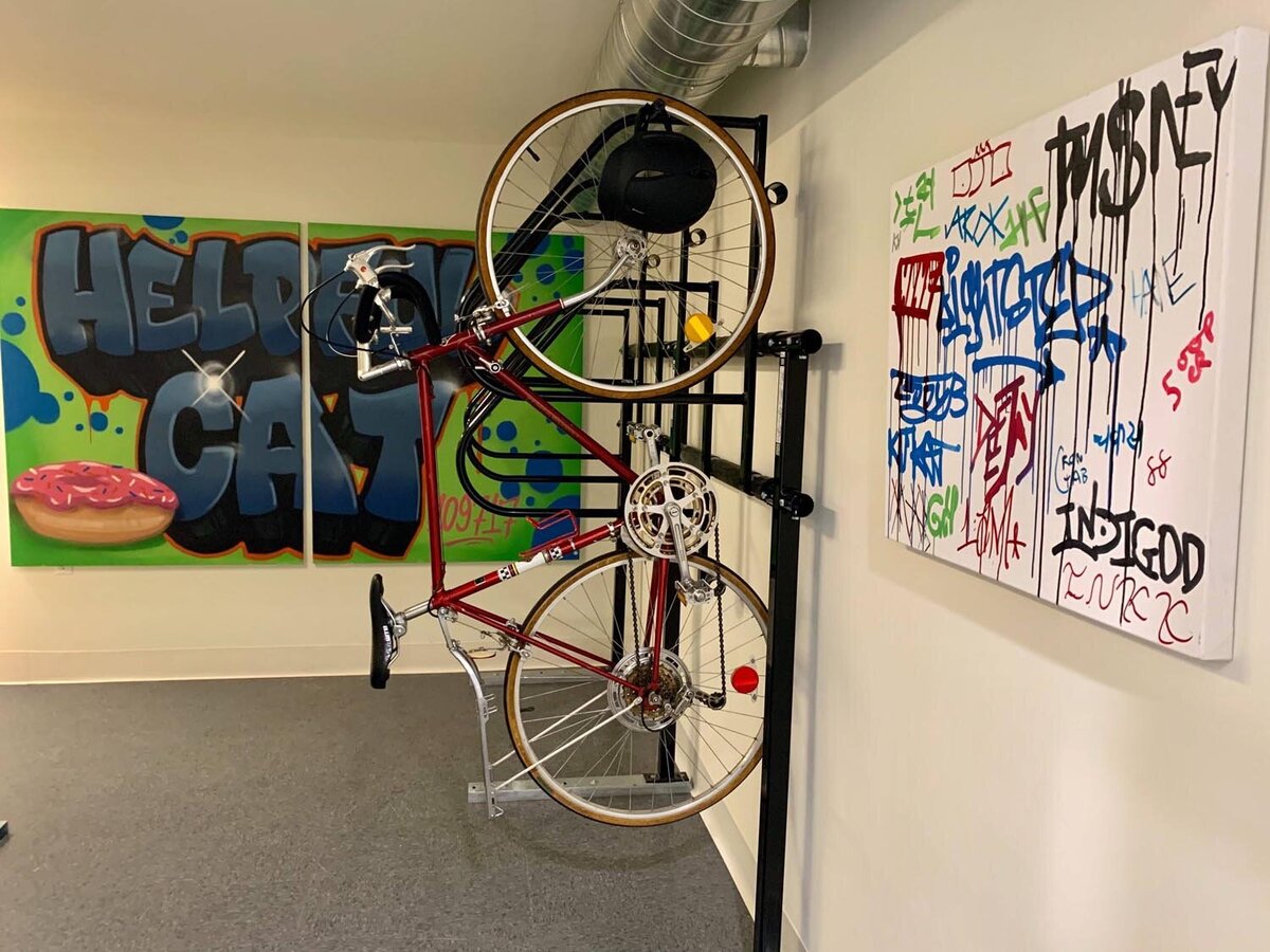 Bike storage area with graffiti artwork and a red bicycle mounted on a black wall rack.