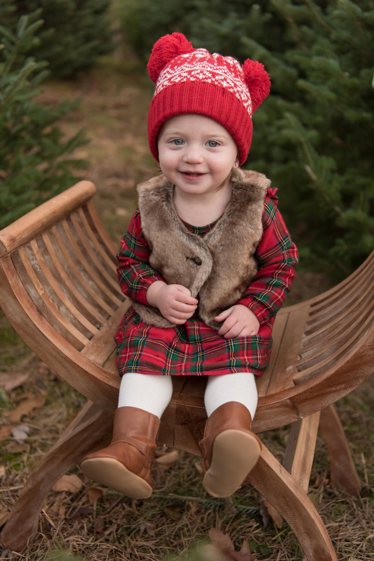 Young girl in red hat sitting on brown bench and smiling at the camera