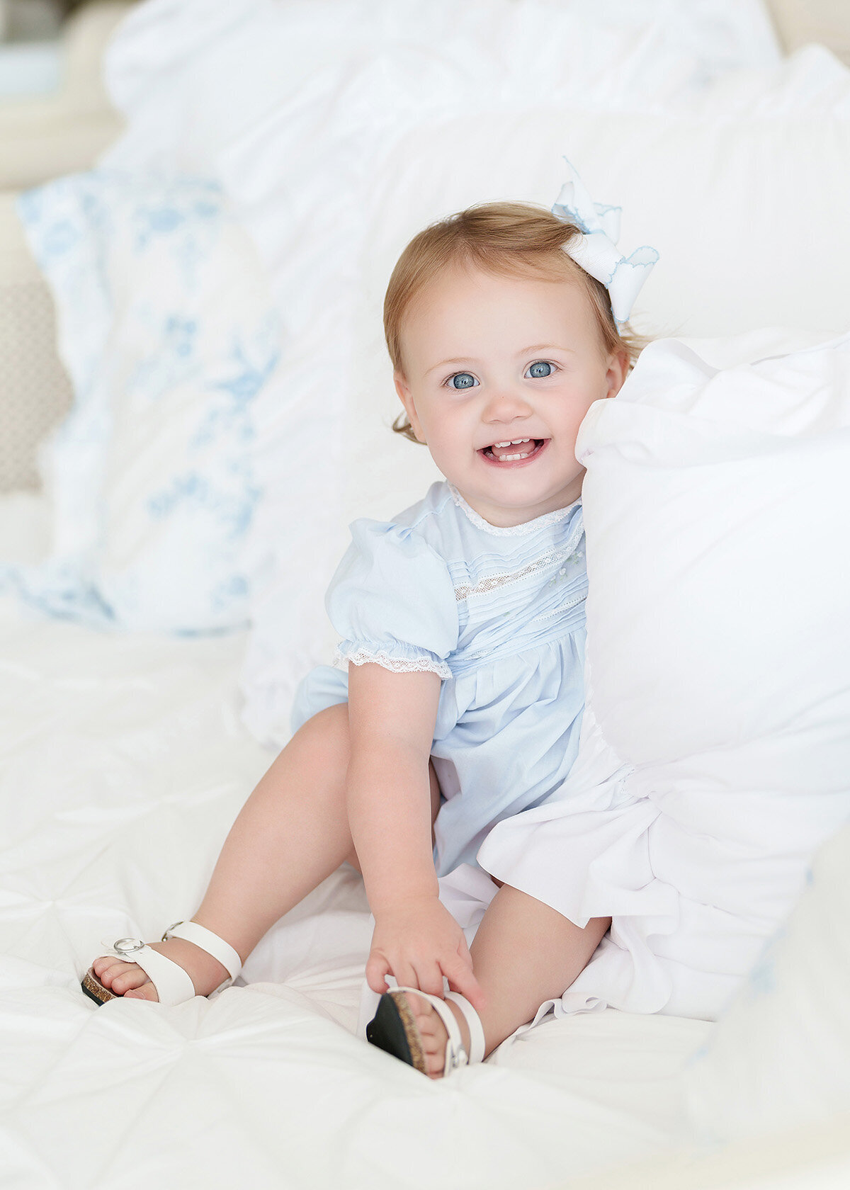 baby girl photographed in luxury studio for her first birthday she is wearing a blue feltman brothers grandmillenial style outfit