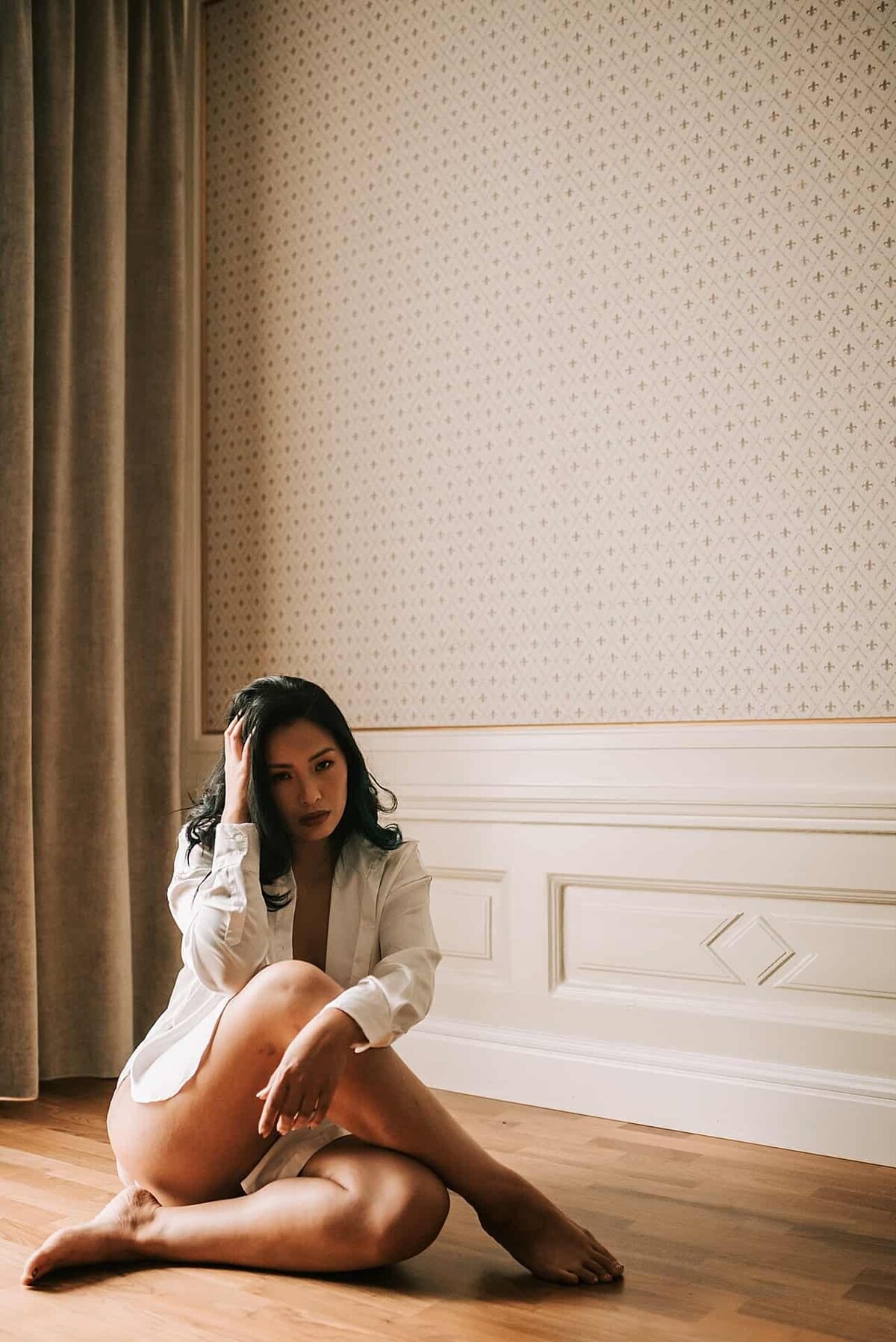 En kvinne sitter på gulvet i et stort rom  på boudoirfotografering i Oslo.