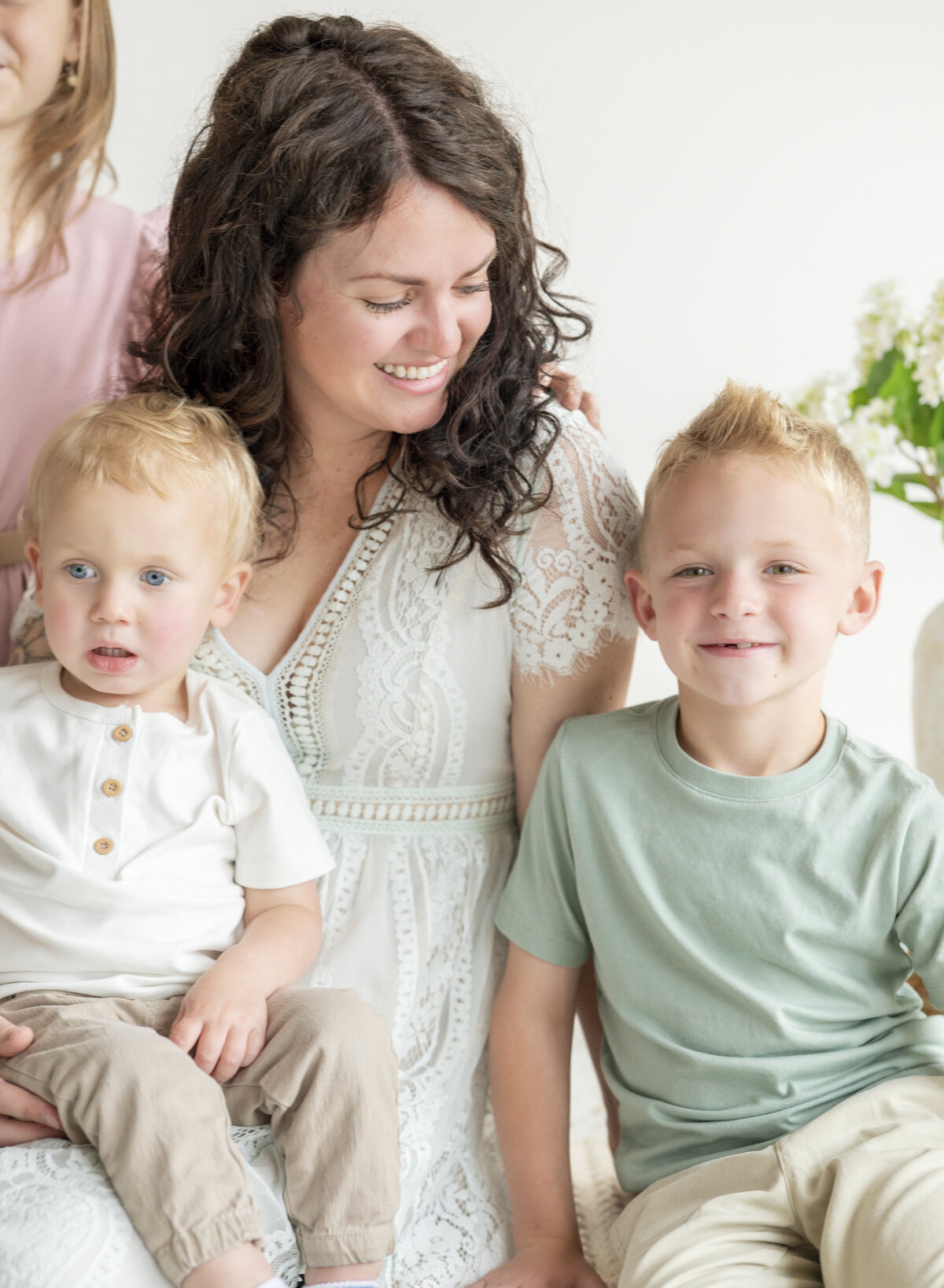 Mom smiling with her three young children on a couch during a relaxed lifestyle family photography session.
