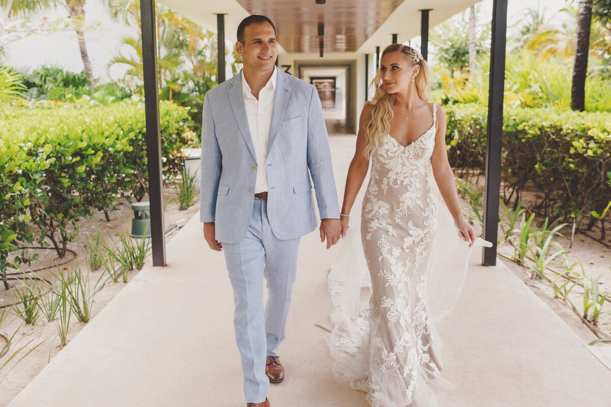 Bride and groom holding hands and walking on pat at Finest Playa Mujeres Cancun