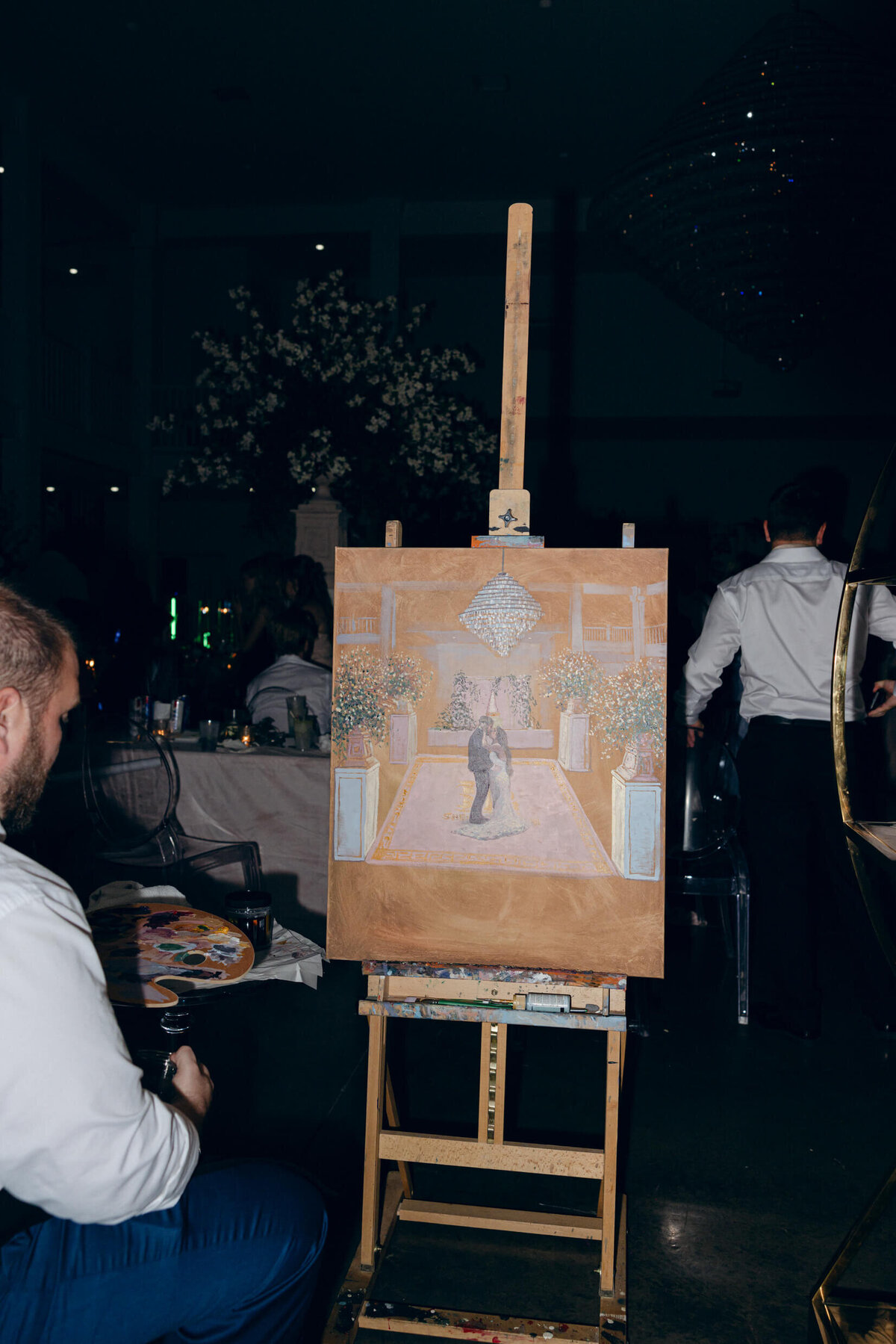 A wedding photo of a live painter painting the bride and groom during their first dance at Legacy Acres