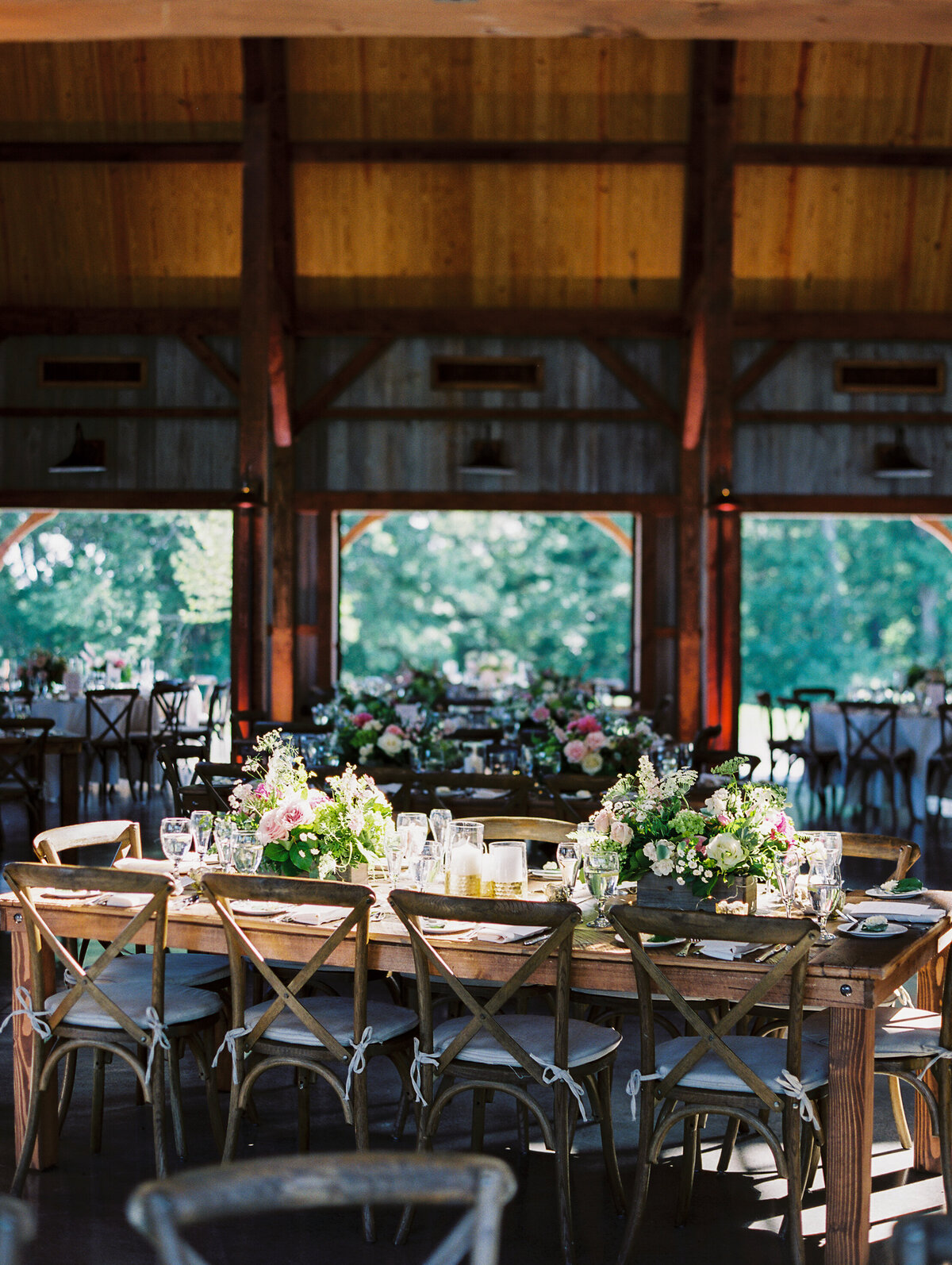 Wooden tables with  floral centerpieces and wooden chairs