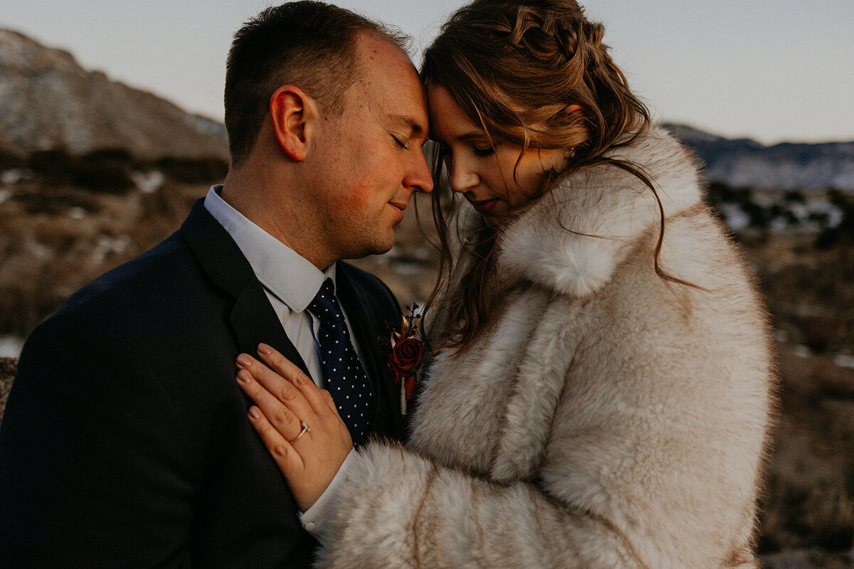 newlyweds holding each other close on the snowy Sandia mountains