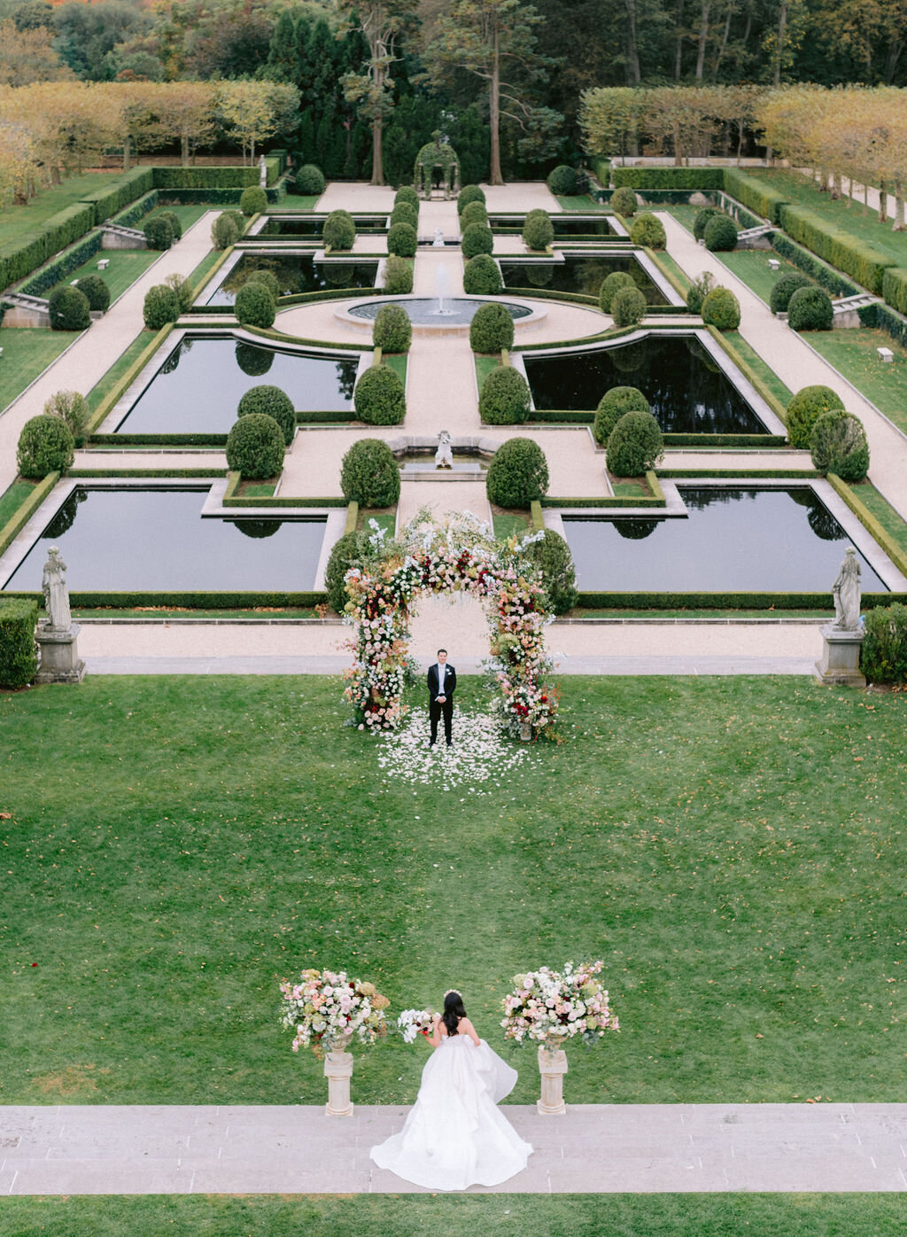Bride walking towards groom in European style gardens