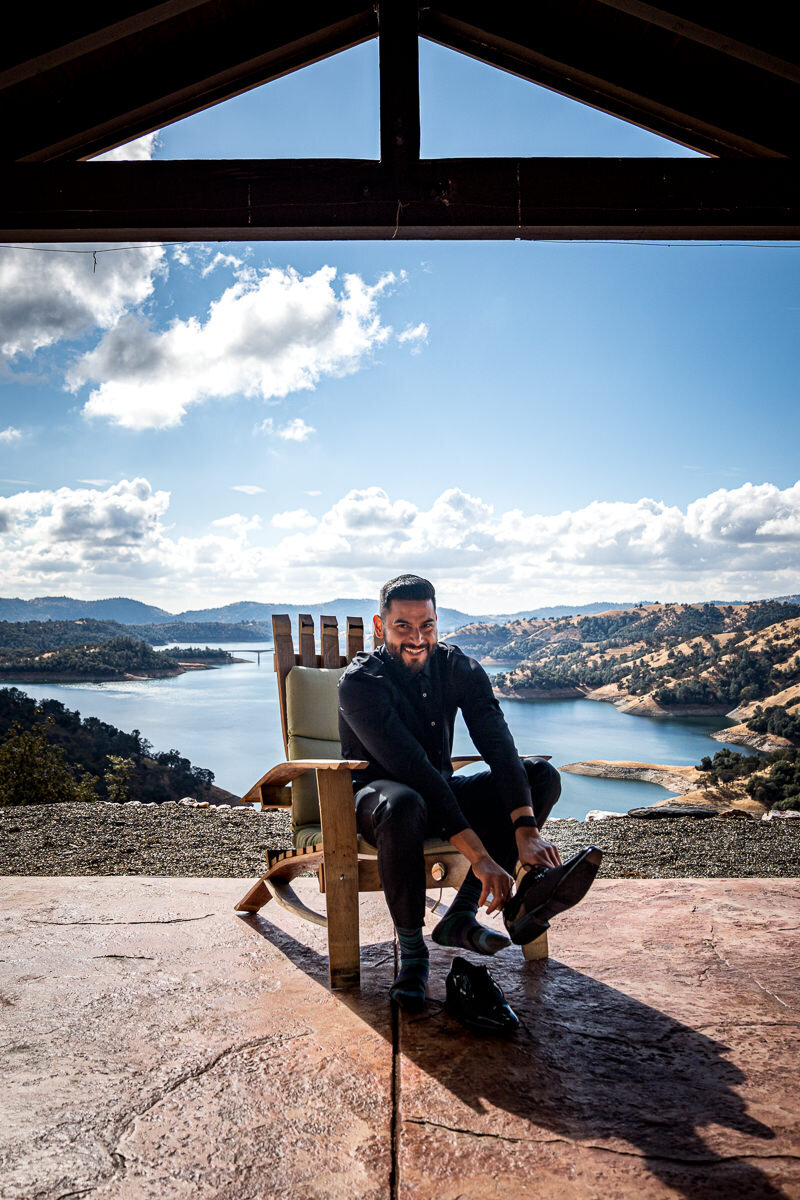 A classic portrait of the groom putting on his shoes with a gorgeous view, blending rustic charm with timeless style.