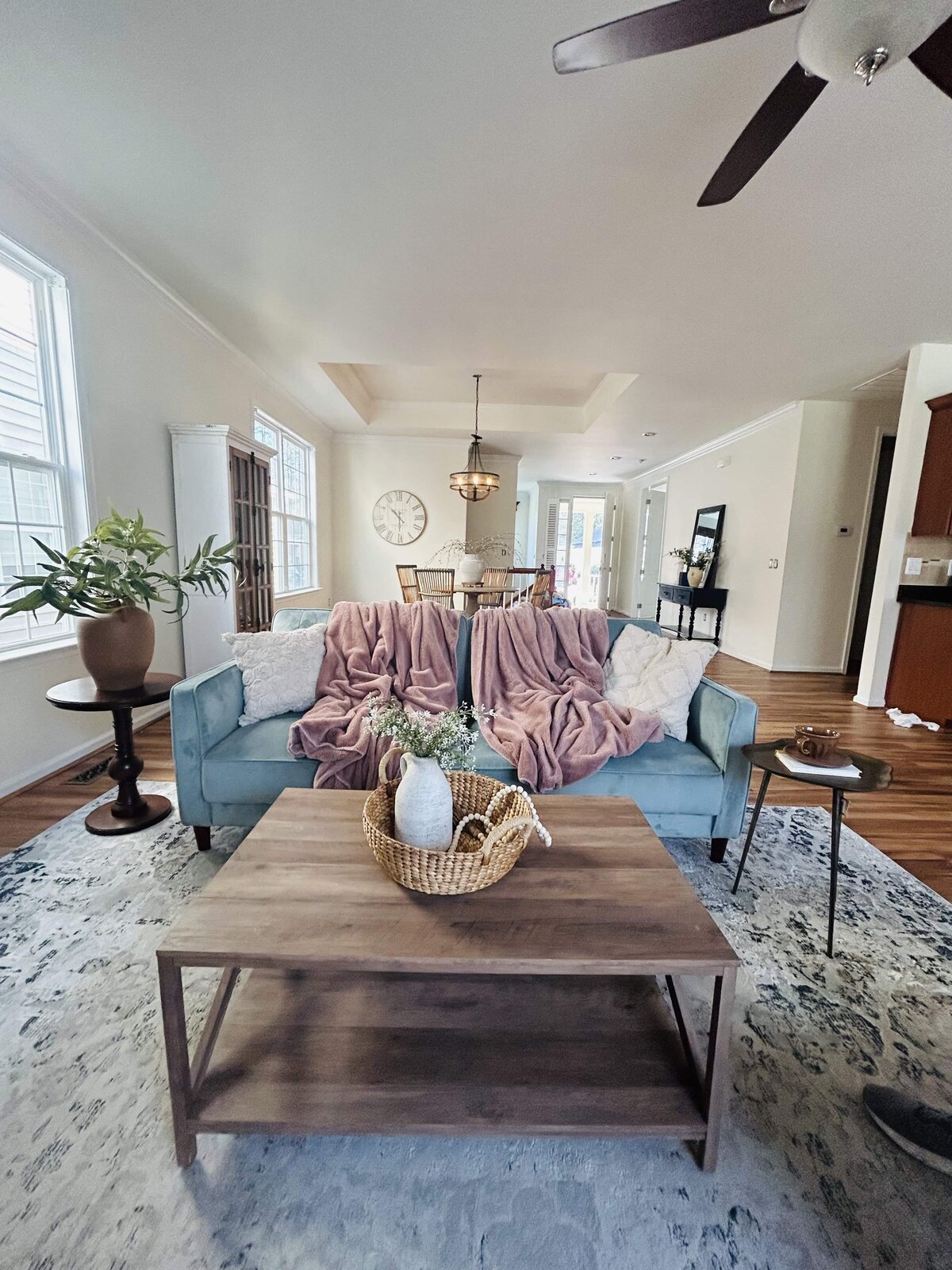 Bright living room staged with gray sofa, floral accent chairs, and patterned rug — Williamsburg home staging design.