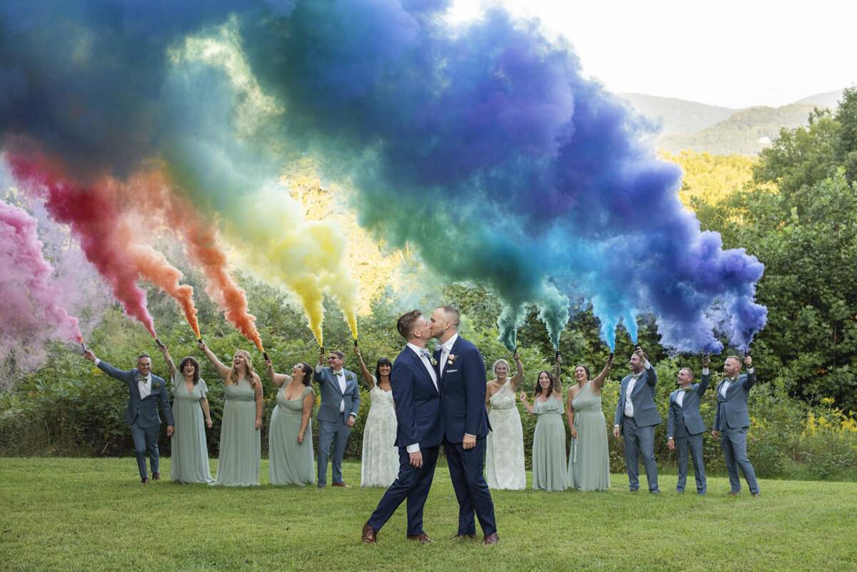 Queer couple kissing under rainbow smoke bomb