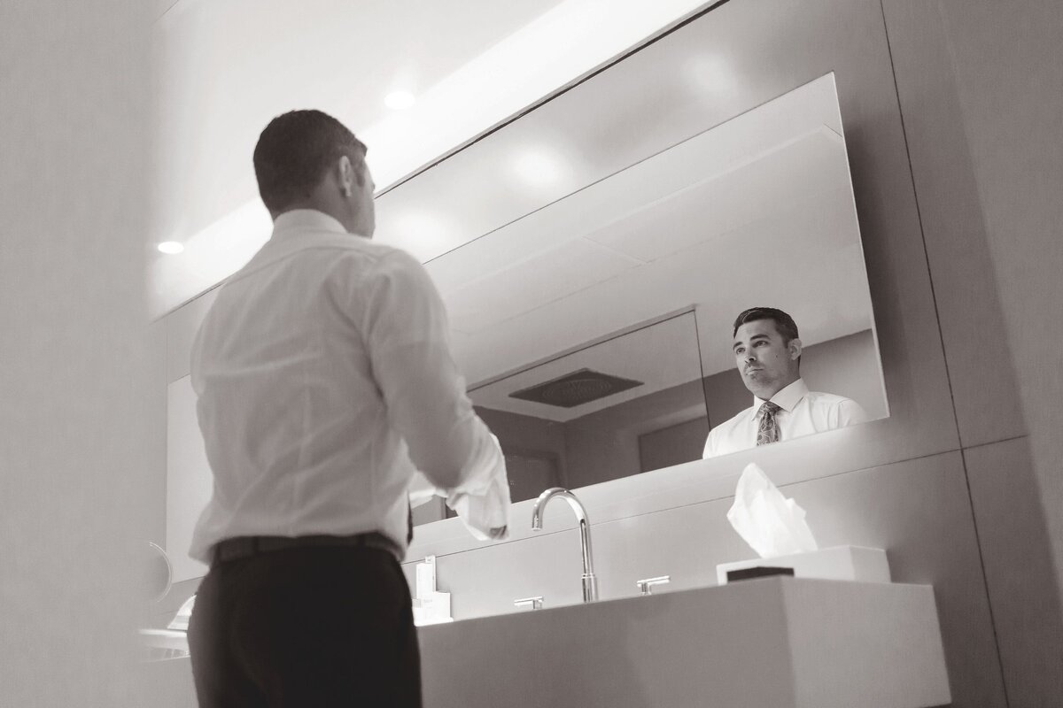 Groom looking in Mirror while getting ready for wedding.