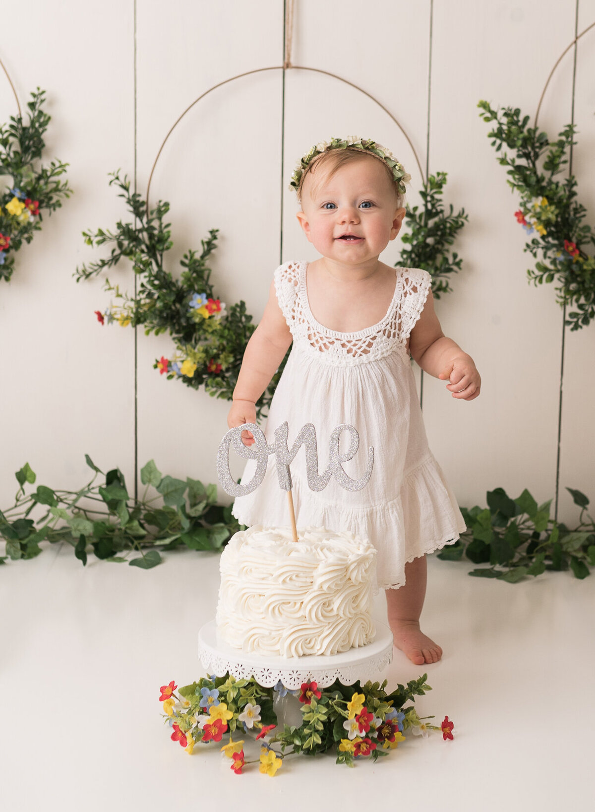 Standing newborn cake smash portrait in white background with green leaves