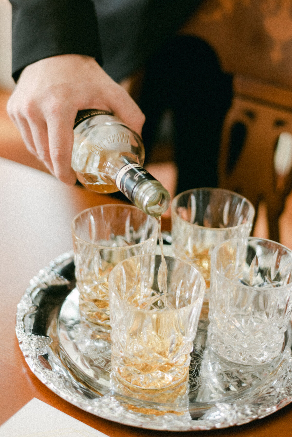 The groom is serving wisky in an image captured by wedding photographer Hannika Gabrielsson.