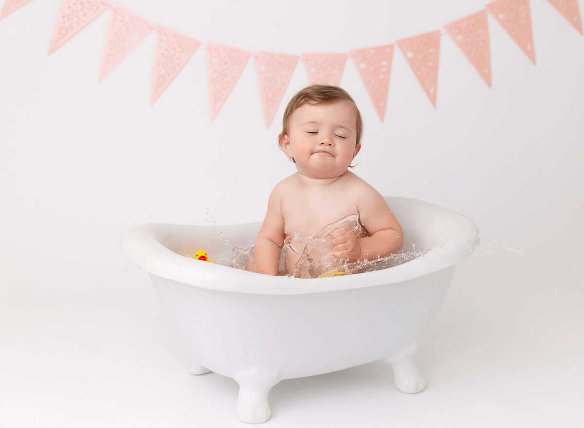 happy baby girl in splash bubble bathtub during cake smash photoshoot in New york city 