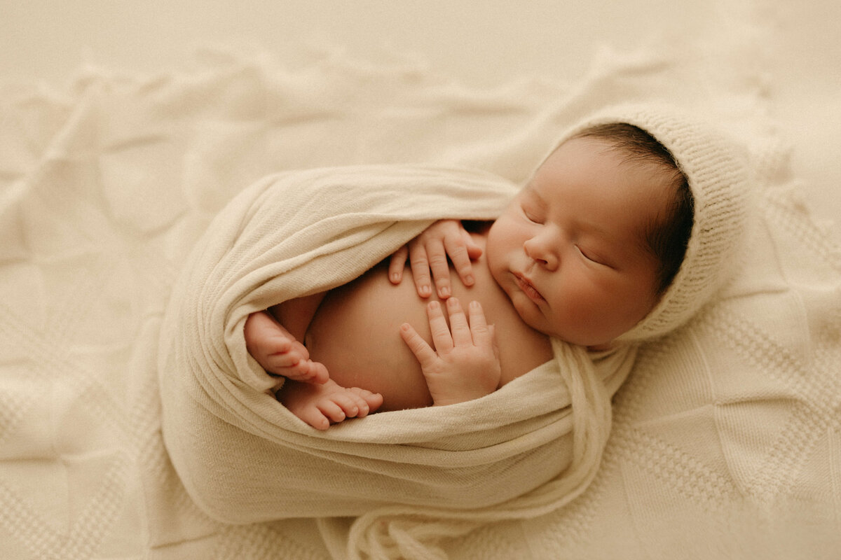 Newborn swaddled in white wrap during clean, minimalist Nashville TN studio session