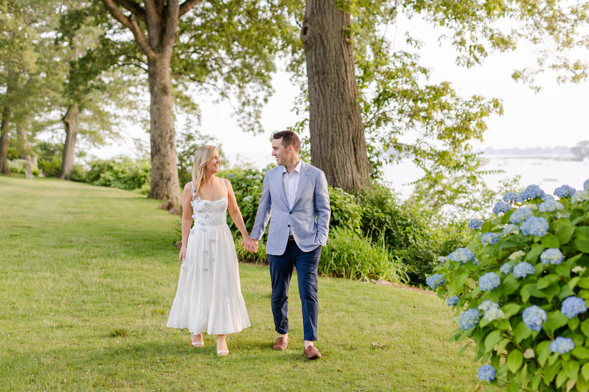couple holding hands walking in the Wainwright House gardens during summer reception dinner on the lawn