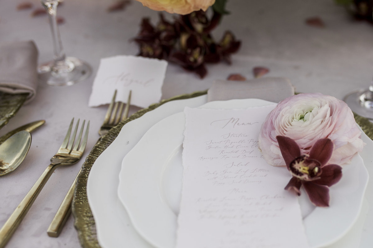 Wedding table set up with pink flowers and invitation on top