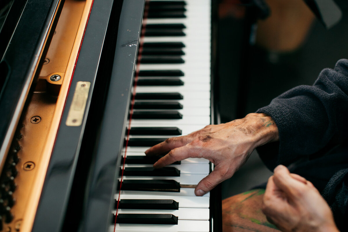 Backstage reportage foto van acteur aan de piano. Je ziet zijn handen van boven op de toetsen.