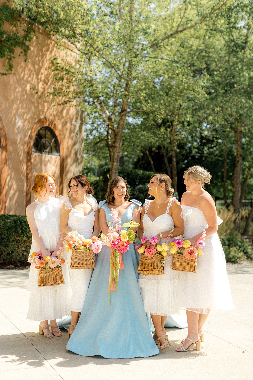 Bridesmaids smiling around bride holding flower baskets at the Club Corazon