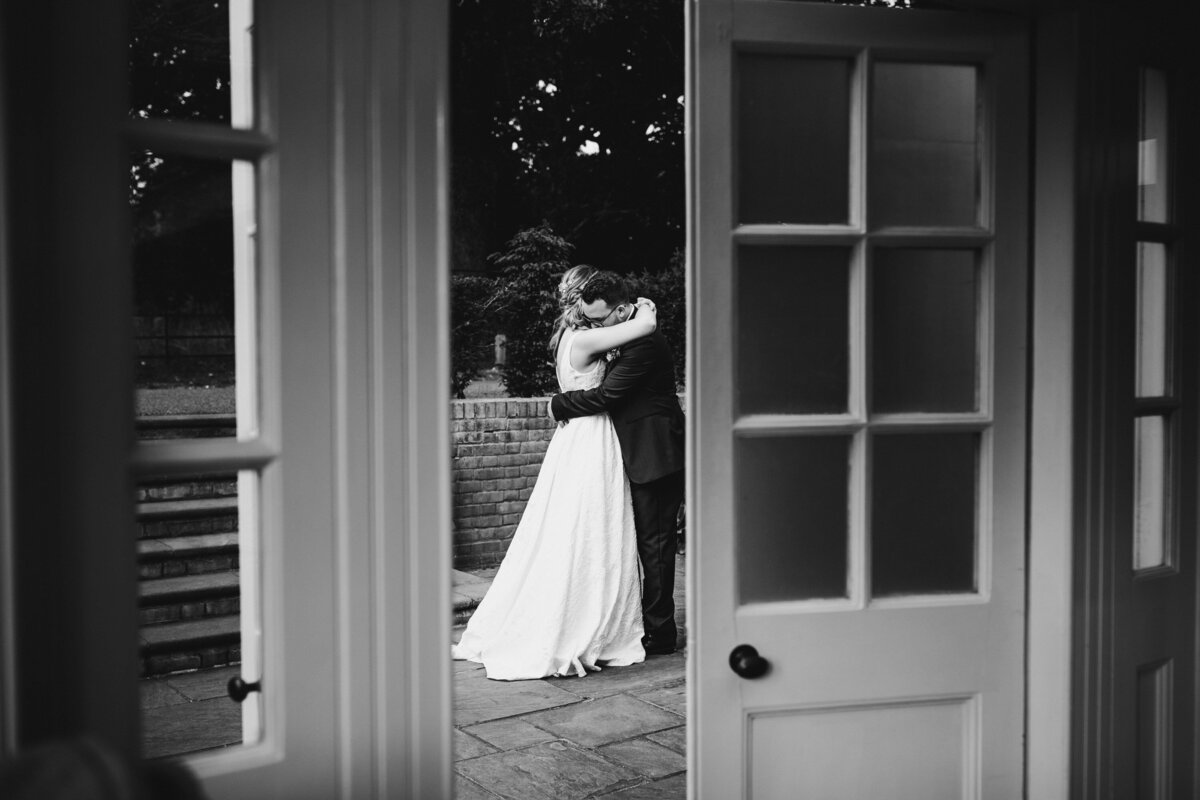 Black and white photo of couple embracing in courtyard
