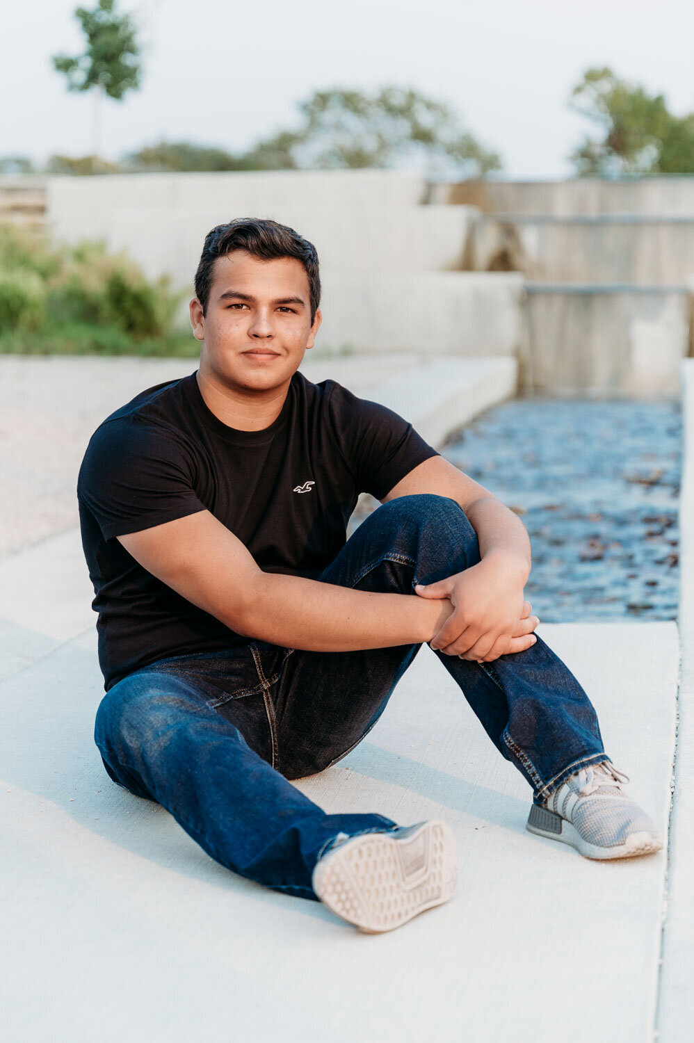 SENIOR BOY SITTING IN FRONT OF A WATERFALL