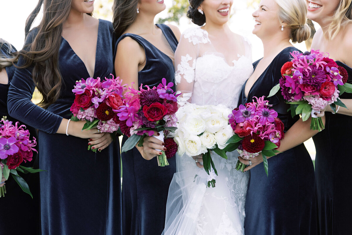 bridesmaids in navy dresses with orchid bouquets