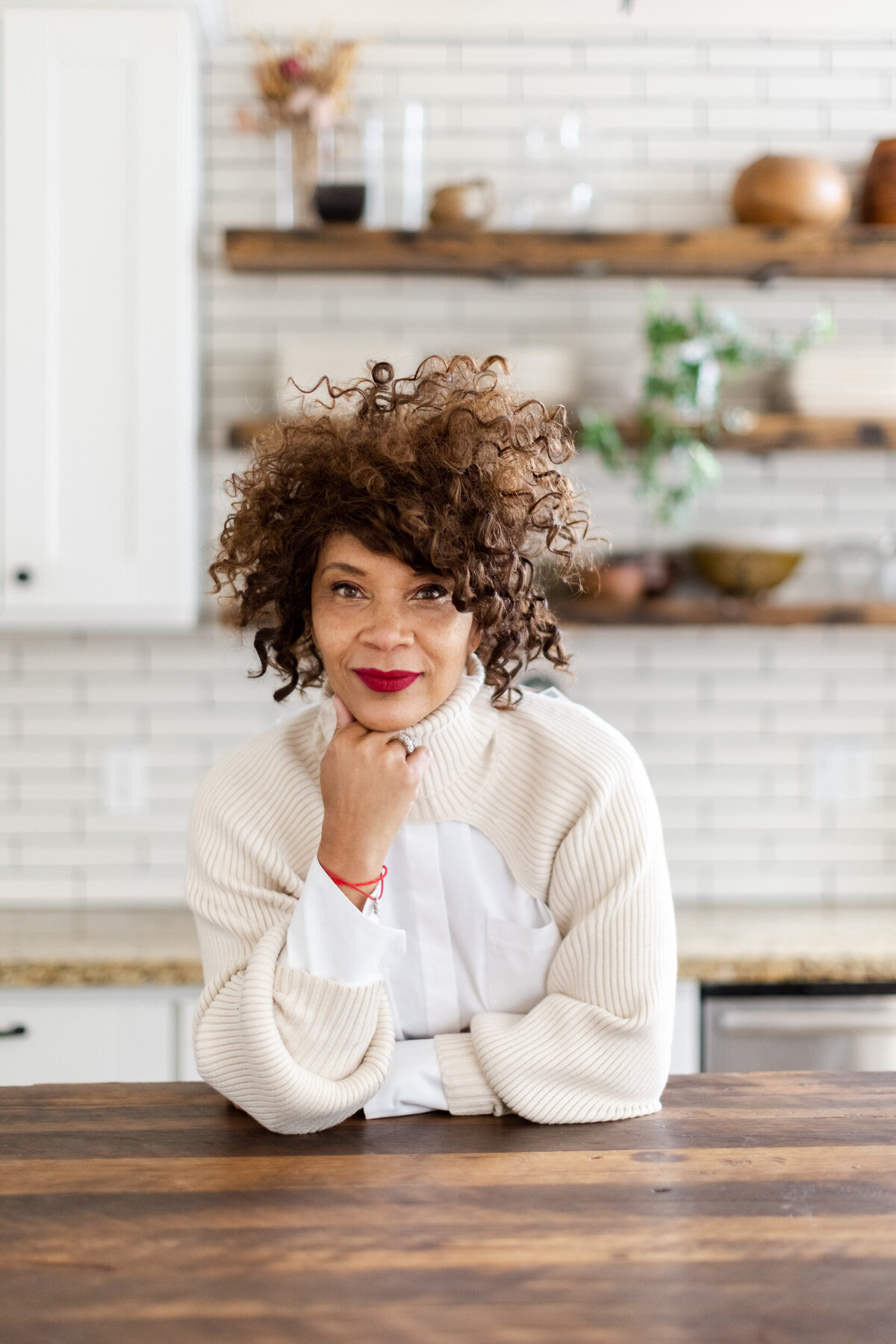 Woman wearing white and red lipstick leaning against a counter in a kitchen in San Francisco.