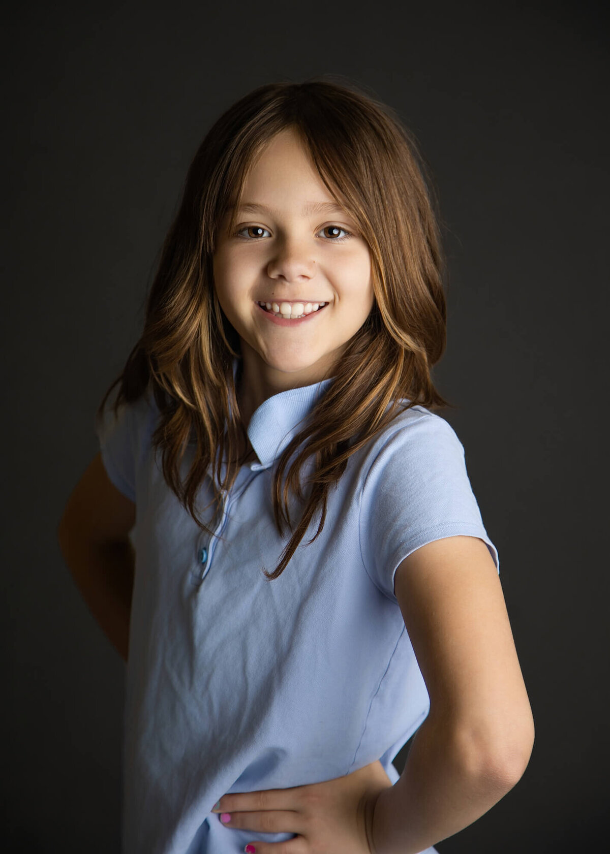 Brown haired girl in a light blue school uniform polo posing for a school portrait